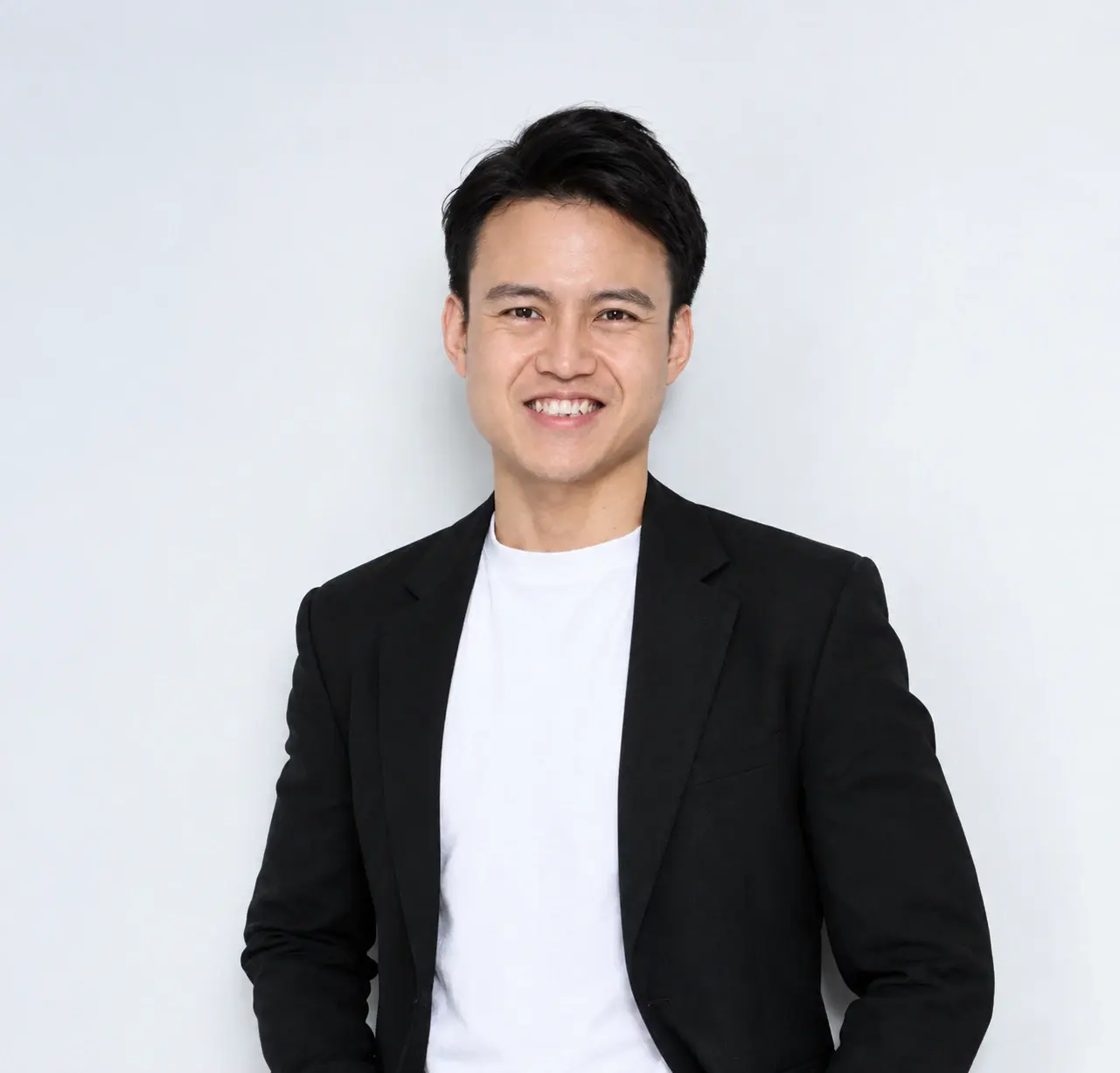 Caleb Peh in a black blazer and white T-shirt, smiling